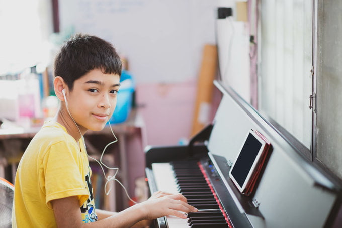 Little boy learning practicing piano online digital tablet